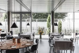 Modern restaurant interior with set tables, large windows, and a floral centerpiece.