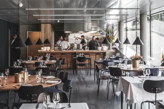 Modern restaurant interior with an open kitchen and chefs.